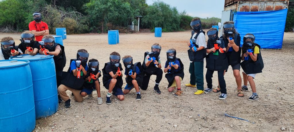 שני משתתפים צעירים בקרב פיינטבול ליד מכולה כחולה